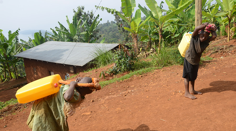 Two young girls carry jerrycans of water in Rusizi District. MPs have tasked the Ministry of Family promotion to speed up the establishment of two orders that will implement the provisions of the law relating to the protection of children. / File