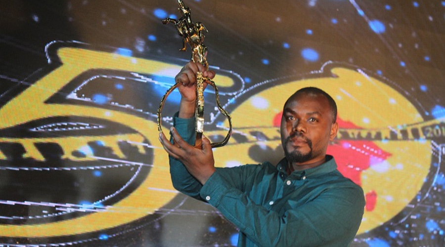 Joel Karekezi shows off the award he won at FESPACO in April. / Courtesy