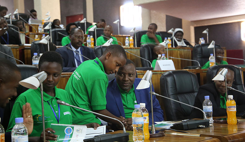 State Minister for Primary and Secondary Education, Isaac Munyakazi consults with one of the young delegates at the National Children Summit held on Wednesday at parliament. Looking on (right) is Nadine Umutoni Gatsinzi, the City of Kigali vice mayor in charge of socio-economic affairs. Craish Bahizi. 