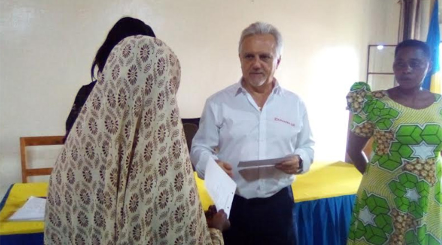 Giancorlo Davite, Director General of Kipharma (L) and ES of Rwezamenyo (far right) give health insurance cards to a vulnerable residents. / Courtesy photos