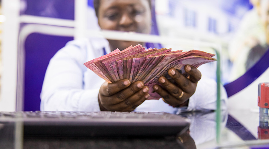 A bank teller counts money before giving it to a client. Ejo Heza, a pension scheme intended to ensure the welfare of informal workers is set to get a boost in the next fiscal year. 