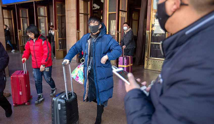 Travelers wear face masks as they walk outside of the Beijing Railway Station in Beijing, Monday, Jan. 20, 2020.