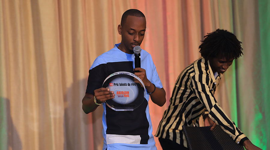 Comedian Michael Sengazi shows the audience his RFI Talent du Rire prize during his performance.