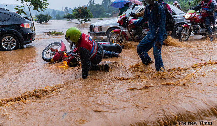 Vehicles and people wade through a flooded street during heavy rains on Kinamba-Gakiriro-Kagugu road in Gasabo District in Kigali on January 28, 2020. The road was impassable for the better part of Tuesday evening due to flooding that left people stranded for hours on either side of the road.  Photo: Emmanuel Kwizera