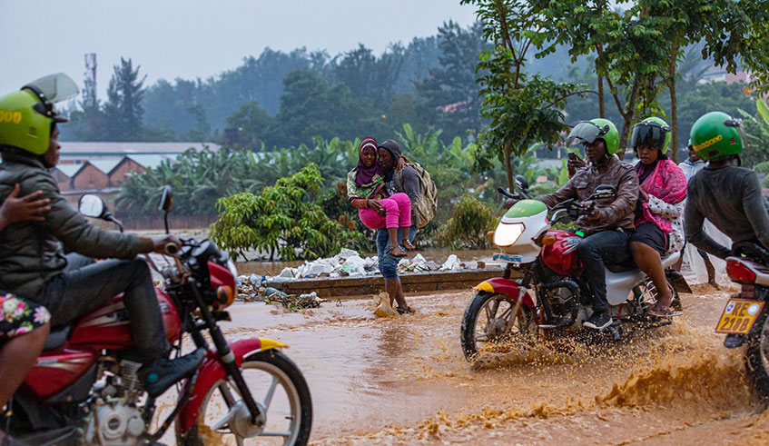 People struggle to navigate through a flooded road. Heavy rains over the last few days caused the death of 19 people and damaged a lot of property. / Photo: E. Kwizera.