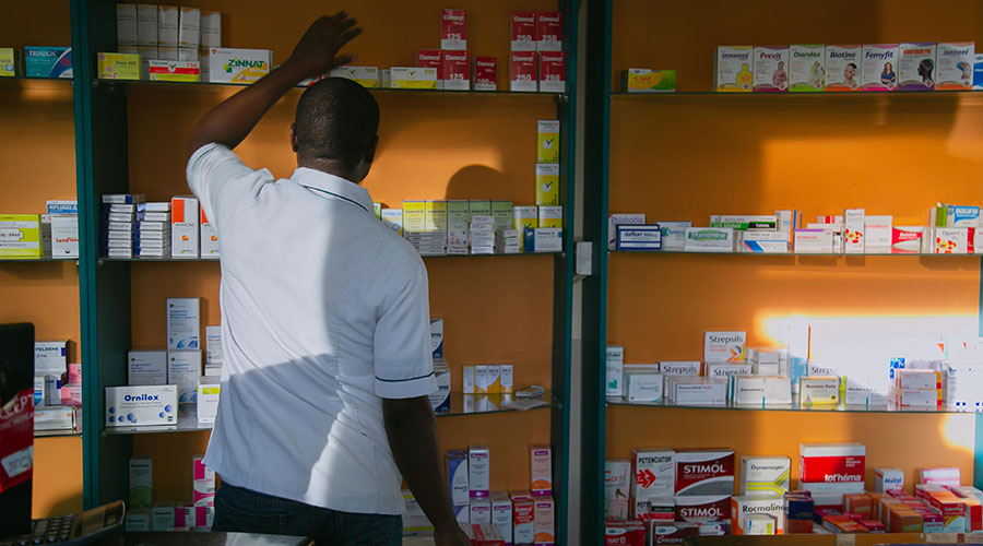 A pharmacist searches for medication on the shelf in Kigali. / Bahizi Craish.