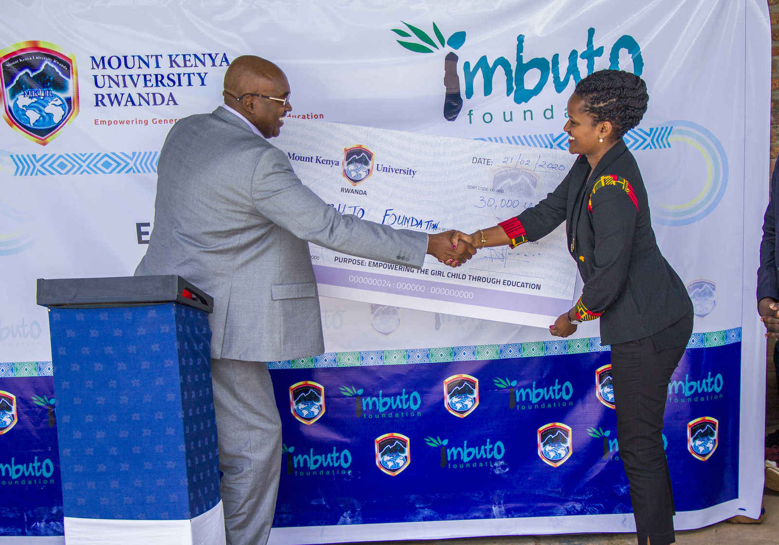 Chairman and Founder of Mount Kenya University, Prof Simon Gicharu (L) hands over a $30,000 cheque to the Director General of Imbuto Foundation, Sandrine Umutoni.  