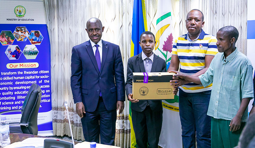 Enock Ntivuguruzwa from GS Rebero receives a laptop as Minister Mutimura and his relatives look on. / Emmanuel Kwizera.