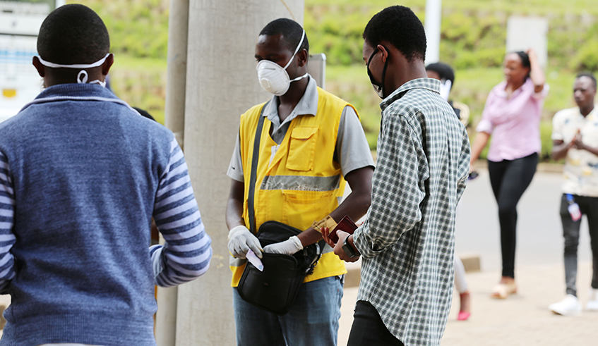 A mobile money agent and his clients wear facemasks in Kigali yesterday (Craish Bahizi)