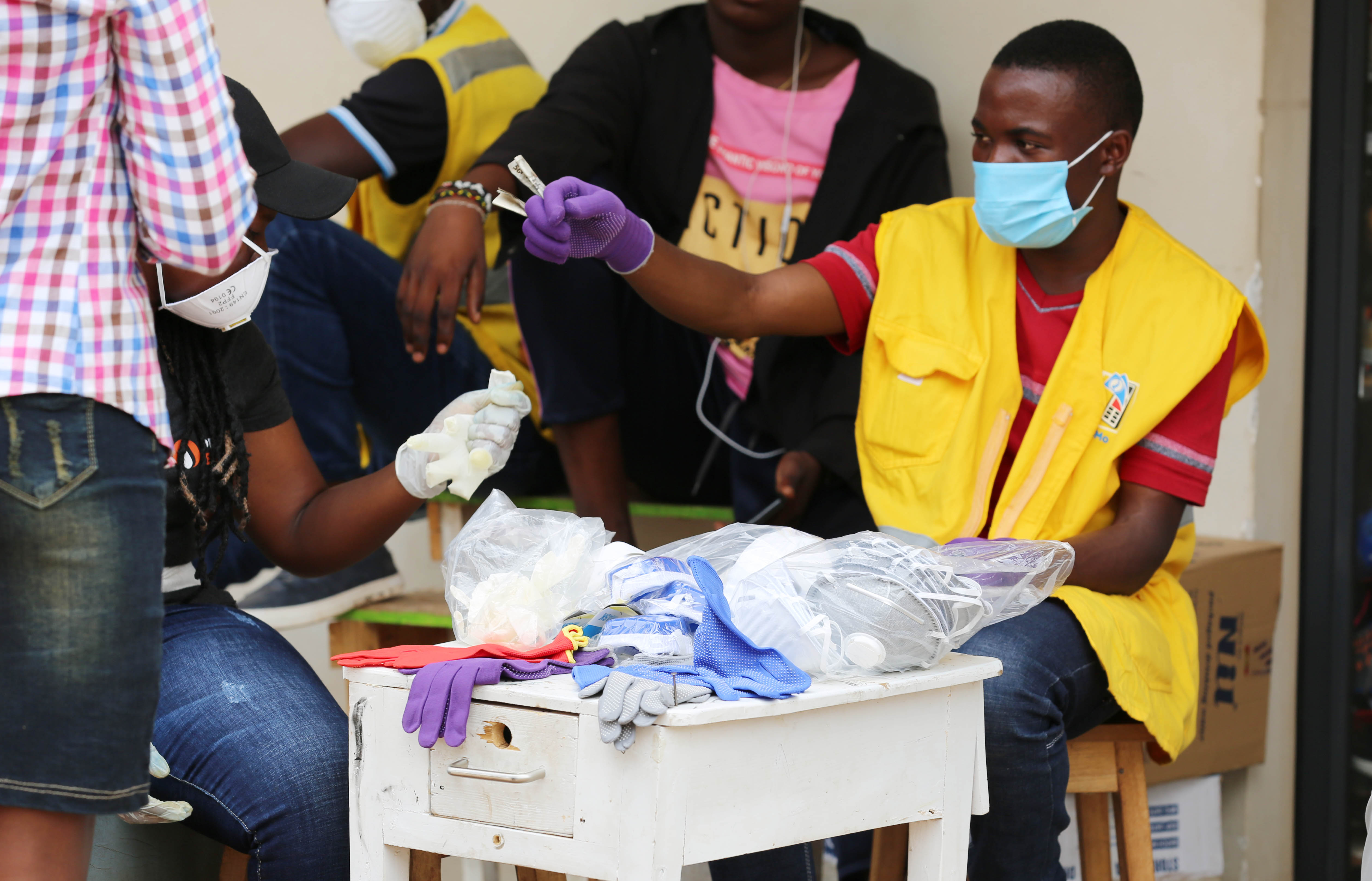 A mobile money agent and his clients wear facemasks in Kigali yesterday (Craish Bahizi)