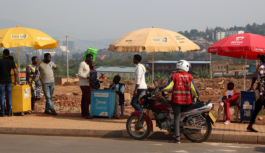 Mobile money agents carry out transactions for customers on a street in Kigali. / Photo: File.