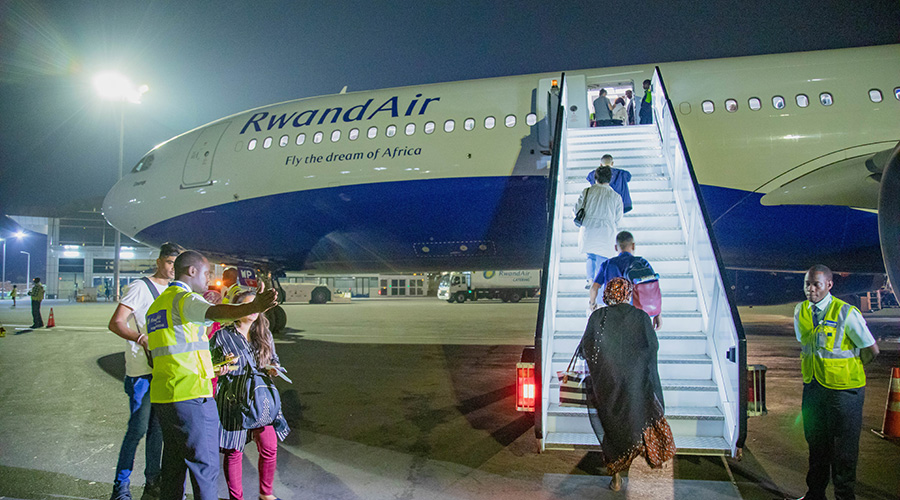 Passengers board a RwandAir flight at Kigali International Airport. On Thursday, March 19, the national carrier announced it will suspend all flights for a period of 30 days as part of efforts to contain the spread of coronavirus. 