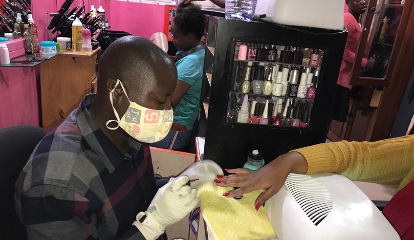 Nuwagaba while painting a clientu2019s nails at the salon in Remera. / Joan Mbabazi.