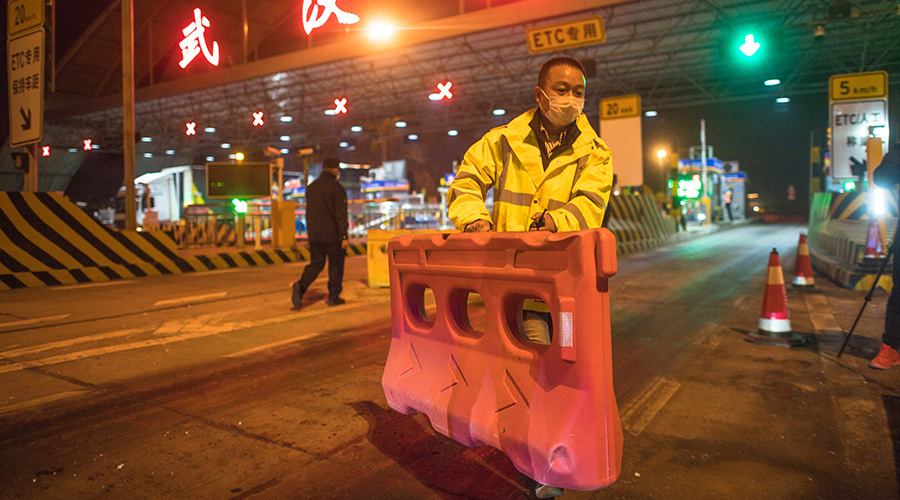 A staff member removes a barricade at an expressway toll station in northern Wuhan, central China's Hubei Province, April 8, 2020. 