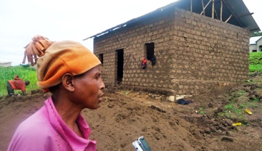 Beatha Mukangango, a genocide survivor speaks to a journalist in front of her house that was under construction in Ruhango. / File.