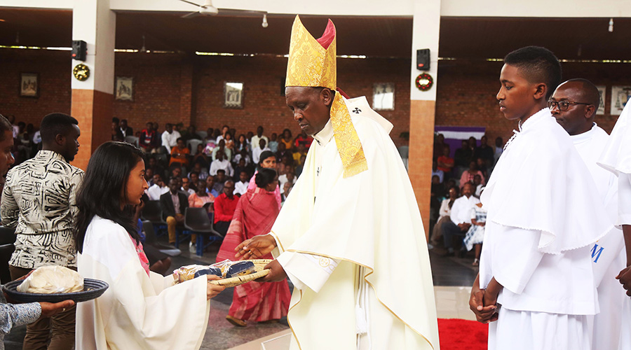 Archbishop of Kigali Antoine Kambanda blesses a believer who brings offerings during the Christmas mass. 