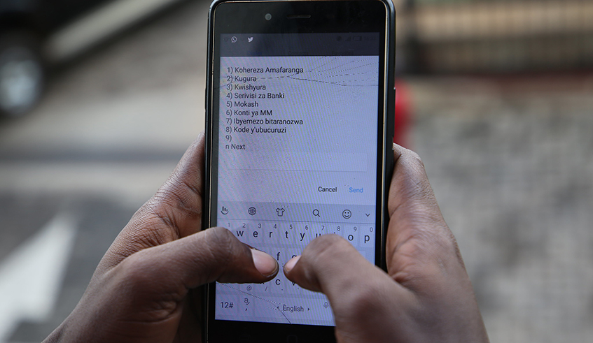 A client checks the balance on his mobile money account. / Craish Bahizi.