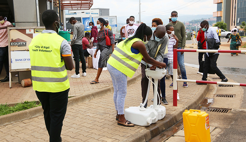 City of Kigali youth Volunteers help people to wash their hands at downtown taxis park on May 4, 2020. / Craish Bahizi.
