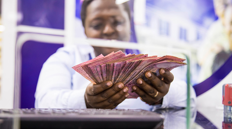A teller counts money in a bank. The governmentu2019s borrowing will increase next fiscal year with revenues expected to drop. 