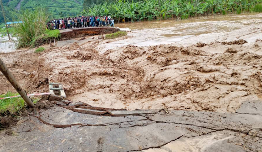 Residents in Nyabihu District watch helplessly as a bridge is submerged by raging floods on May 7. Government says it plans to spend at least Rwf1 billion on the rehabilitation of Mugogo lowland that straddles Musanze and Nyabihu districts in a bid to tackle floods and revive economic activity there.. / Photo: Courtesy.  