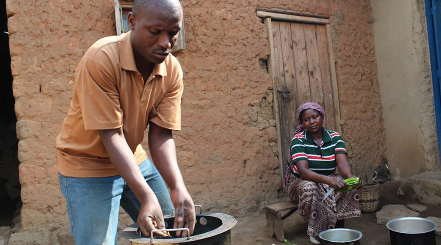 Ju00e9ru00f4me Nzitabakuze lights a fire to prepare food as his wife Nyirashyirambere peels banana. The couple says that redistribution of domestic chores has led to socio-cohesion values within their family. 
