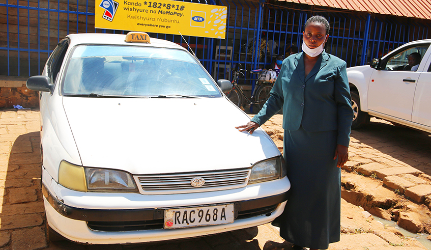 Marie Claire Niyotwagira a taxi driveru00a0 pose near his car after the Interview with Doing Business on Mondayu00a0 in Kimironko Market. /Craish Bahizi.