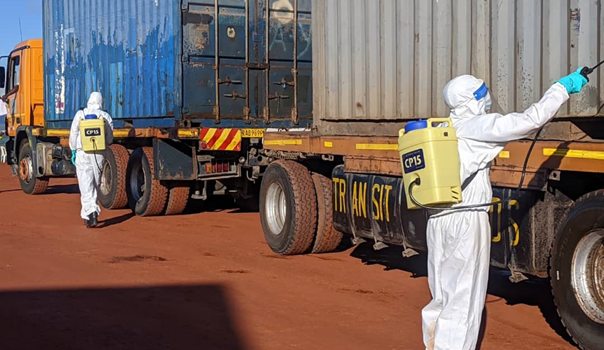 Health workers disinfect cargo trucks at the Rusumo border post recently. / Photo: File.