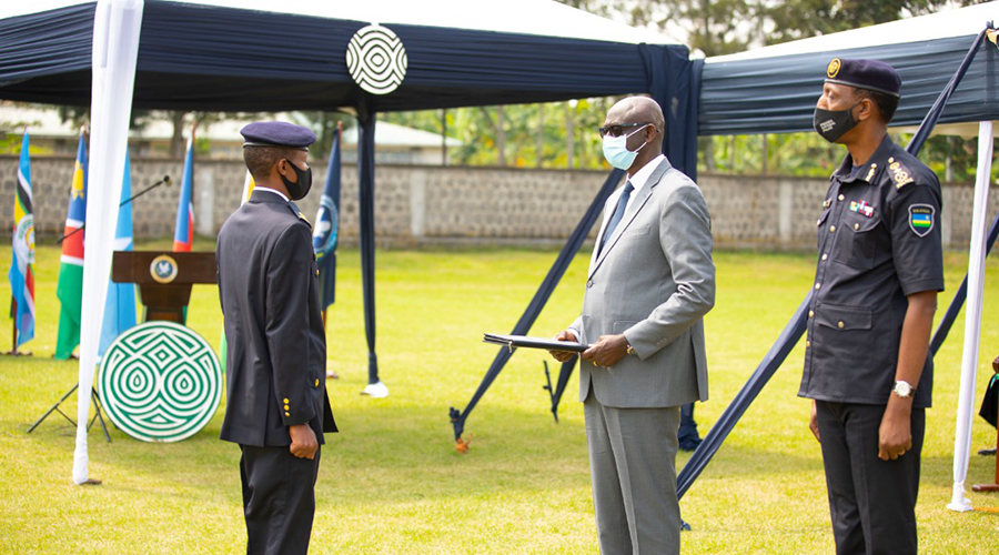 The Minister of Justice and Attorney General gives a certificate to one of the graduands as NPC commandant CP Christophe Bizimungu looks on. 