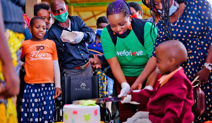 Gaudance, 5, cuts a cake with  artistes Aline Gahongayire (in a green T-shirt)and DeQueen at Kibagabaga Hospital.