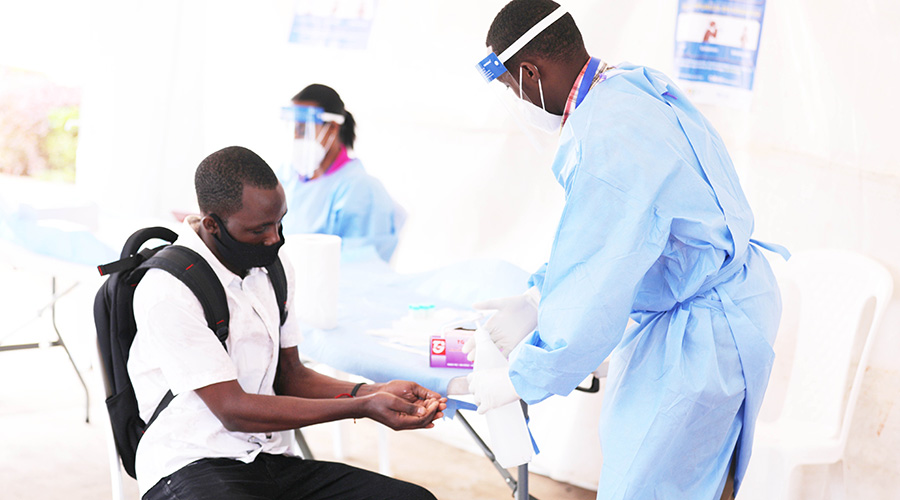 A medical staff sanitizes a citizen's hands before conducting the COVID-19 random test at Amahoro National Stadium on 2 July. 