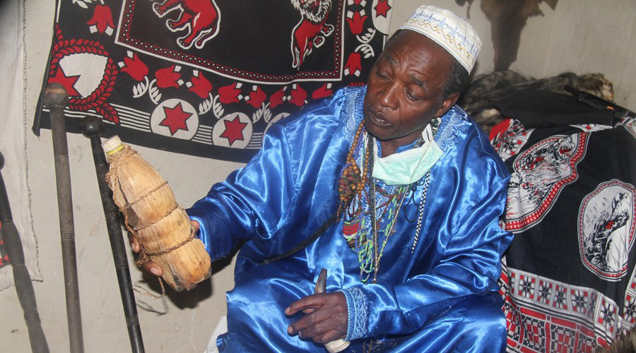 Amos Kafera with a bottle of traditional herbal drink at his shrine in Chitungwiza, Zimbabwe, on July 15, 2020. 