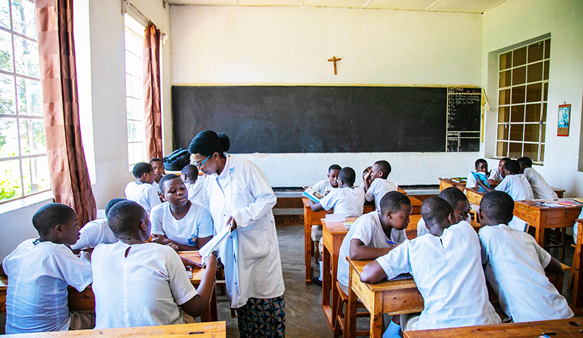 A teacher inspects how students do their teamwork at Institut Sainte Famille de Nyamasheke. 
