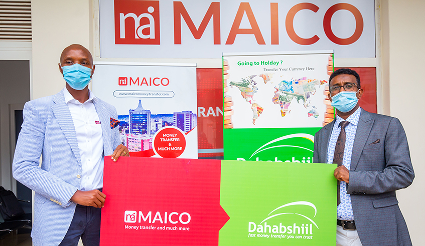 Maico Money Transfer Chief Executive Innocent Higiro (left) and Mustafe Sheikh Adan Amin, the  Managing Director of Dahabshiil in Rwanda, hold a signage during the launch of partnership be- tween the two companies in Kigali on Tuesday, September 29. / Photo: Courtesy.