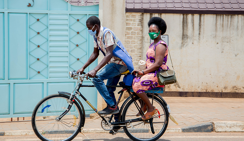 Cyclist transporting a passenger in Kigali. Bicycle taxi operators say they are in a dilemma after they were given a green light to resume operations with a strict condition to wear helmets . / Dan Nsengiyumva