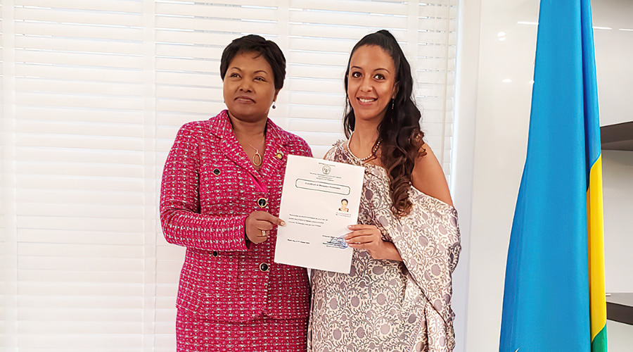 Amb. Mathilde Mukantabana, Rwandau2019s envoy to the United States of America (left), hands a certificate of citizenship to Setti Solomon in Washington on September 25. The Directorate of Immigration and Emigration has granted nationality to 935 foreign nationals from 2009 to date. 