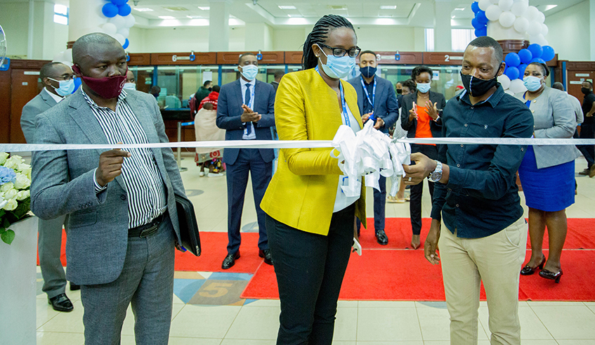 Bank of Kigali Chief Executive Diane Karusisi (centre), assisted by 2 clients, cuts the ribbon during the launch of the One-stop-centre digital booth at the banku2019s headquarters in Kigali on Monday, October 5. / Photo: Dan Nsengiyumva.