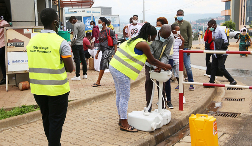 City of Kigali youth volunteers help people at a hand washing station downtown in May. / Photo: File.