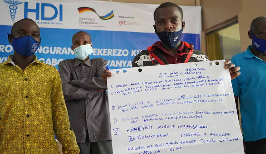 A group of parents pose with a list of committments made during the dialogue between teen mothers and their fathers. They pledged to help their daughters get back up, and continue pursuing their dreams. / Photo: Courtesy.
