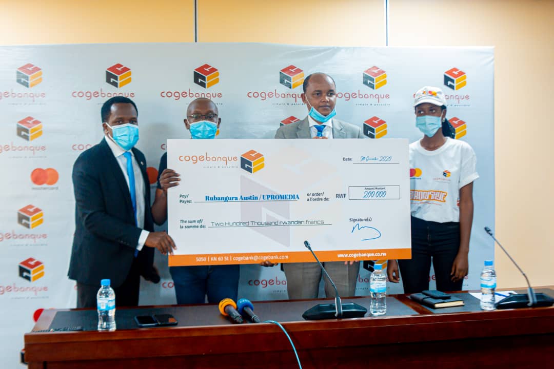 Antoine Iyamuremye, Head of Marketing and Product Development (left), and Songa Rwamugire, Head of Corporate Banking at Cogebanque (2nd right), hand over a cheque to the best user of Mastercard during a news conference on Wednesday, December 9. / Photo: Craish Bahizi.