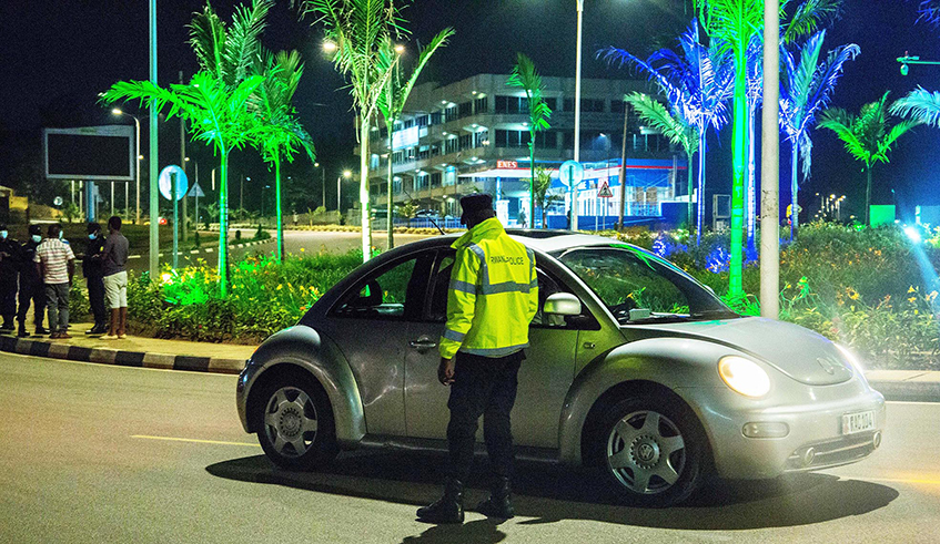 A traffic police officer inspects a car at Kicukiro-Sonatubes roundabout in the capital Kigali. The Government has tightened Covid-19 preventive measures in the wake of rising new infections, including bringing forward curfew time to 9p.m. / Photo: Dan Nsengiyumva. 