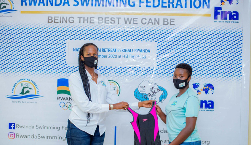 Pamela Girimbabazi, the head of Rwanda Swimming Federation hands over swimming gear to a female member of the National swimming team recently. / Courtesy. 