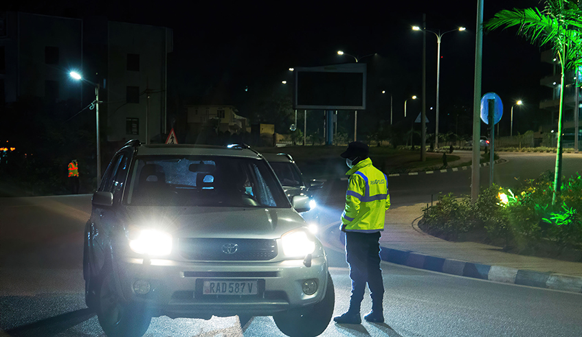 A traffic police officer inspects a car in July last year. According to the police, the number of people arrested and vehicles impounded over the violation of curfew restrictions has decreased, which is seen as a step in the right direction in the fight against the Covid-19 pandemic. / Photo: Dan Nsengiyumva. 