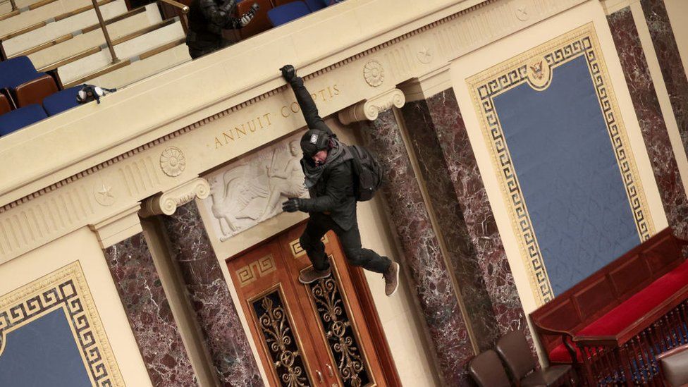 A protester jumps over a balcony to reach the Senate floor. 