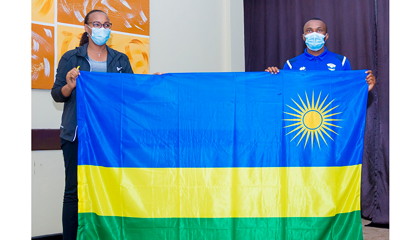 Minister of Sports Aurore Mimosa Munyangaju (L) hands over the national flag to Amavubi captain Jacques Tuyisenge as she flagged off the national football team delegation in Bugesera on Monday. The team will depart for Cameroon on Wednesday. / Courtesy. 