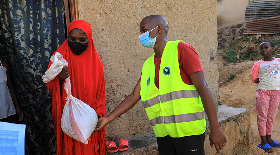 A volunteer hands over a package of food relief to a resident of Rwezamenyo sector in Nyarugenge District during the lockdown on February 2. 