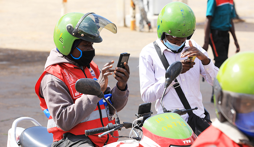 A taxi-moto user pays his transport fee using mobile money . / File