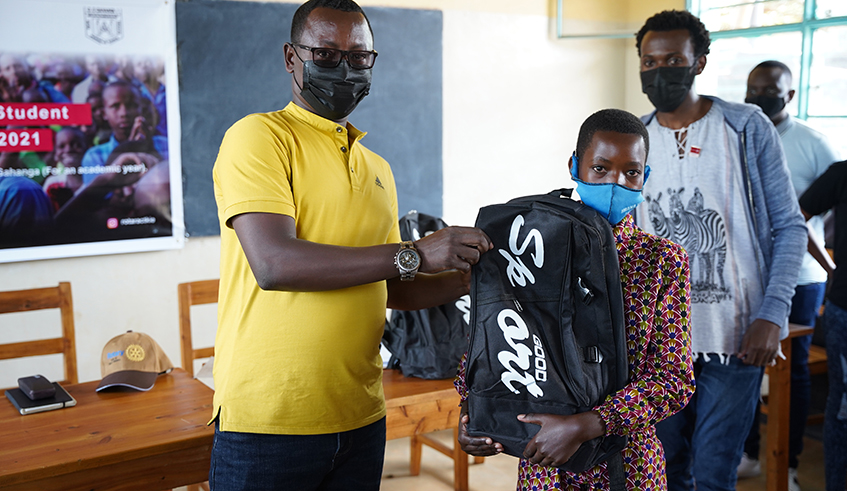 One of the pupils receives scholastic materials from an official at GS Gahanga. / Photo: Willy Mucyo.