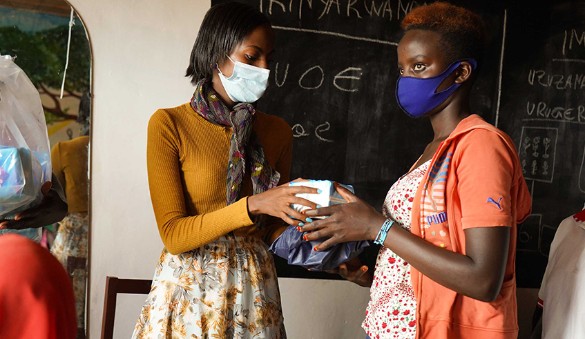 HDI employee hands sanitary pads to a young girl member of the Cyaruzinge community in Gasabo District./ Photo: Courtesy.