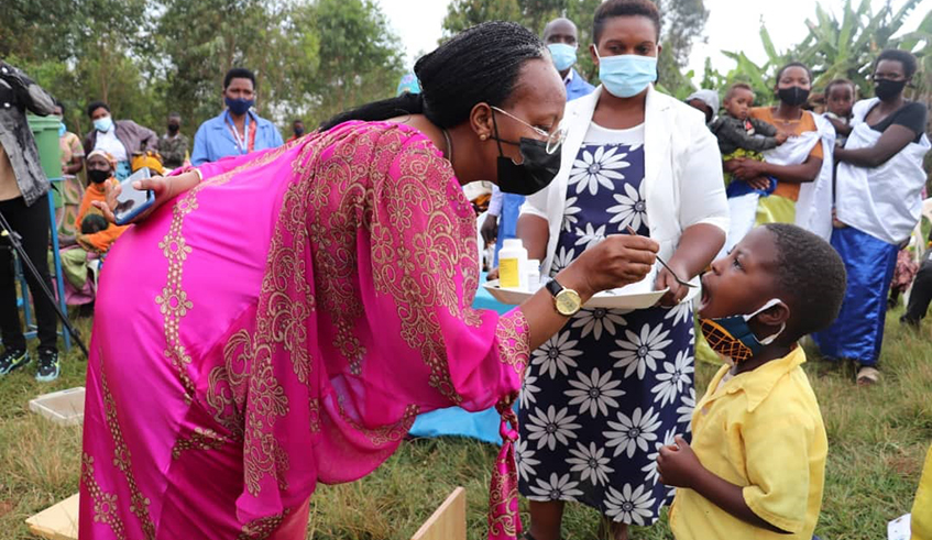 Martine Umubyeyi, a member of the Steering Committee of the National Child Development Agency, administers Vitamin A to a child at Ubunyarwanda Isibo, Rusenge Sector in Nyaruguru District on the occasion of Day of the African Child, on Wednesday, June 16. Sheu2019s flanked by Collette Kayitesi, the Vice-Mayor in charge of Social Affairs, Nyaruguru District. / Photo: Courtesy. 