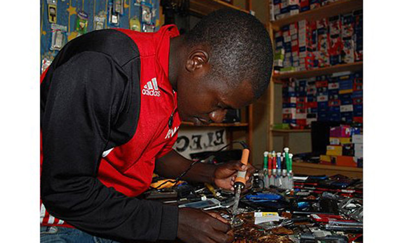 A technician repairs a phone at his shop in Kigali. / Photo: File.
